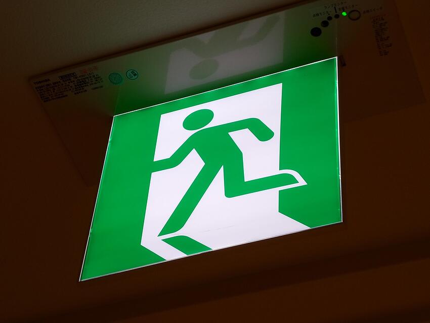 A green illuminated emergency exit sign above a doorway