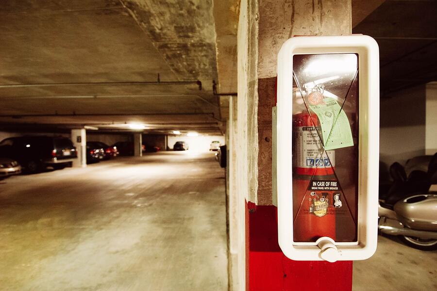 A fire extinguisher cabinet on a dim parking level