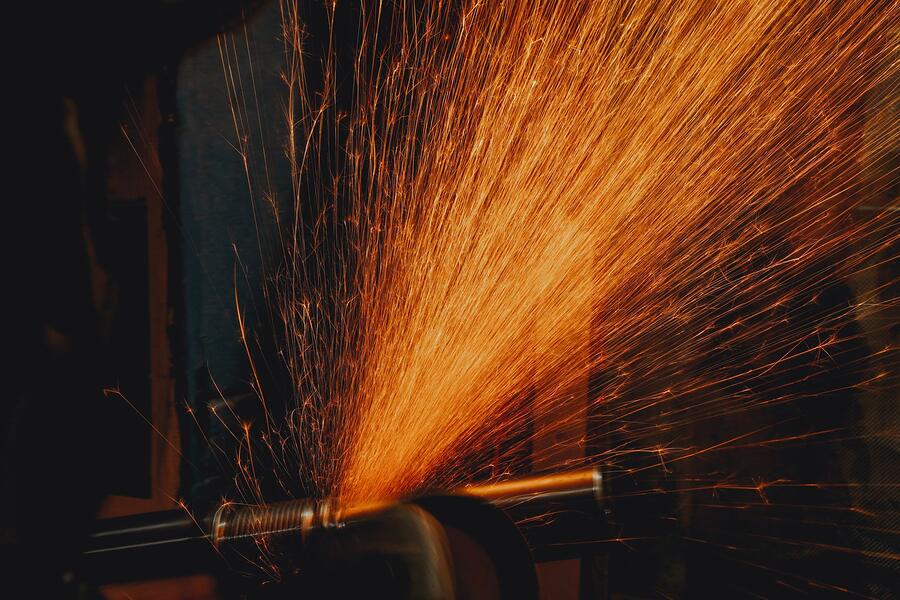 An angle grinder throwing a long fan of sparks across a steel surface