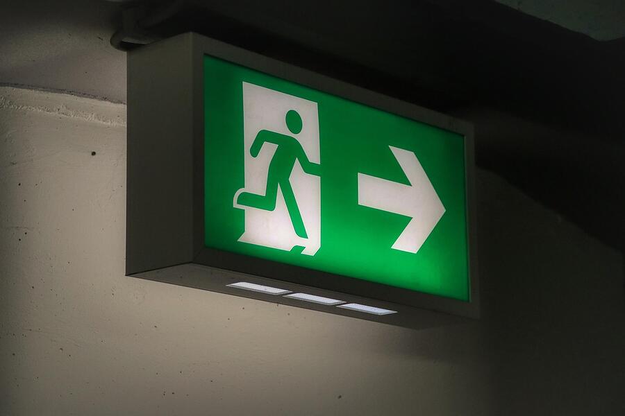 An illuminated exit sign with a directional arrow