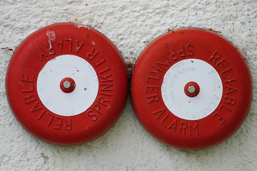 Two red sprinkler alarm bells on the exterior wall of a building