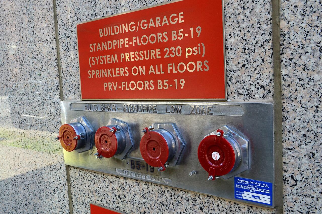 A building standpipe and sprinkler information sign beside its fire department connections